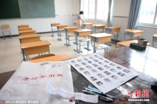 2016年6月3日，北京，东直门中学考点，教室外已贴上了统一印制的考场信息，上面显示着考点编号、名称及具体的考场号。教室内设置了约30个考生座位，座位与座位之间的距离约为80厘米以上。两位考务老师手持一叠写有学生姓名、准考证号的桌签走进教室，按考场座位安排表逐一贴在桌子上。随后，一位老师在黑板上写下了当科开考的科目、考试时间和试卷份数。图片来源：东方IC 版权作品 请勿转载