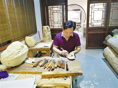 胡建能在即将开放的木雕艺术馆制作木雕。(徐欣摄)